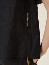 Blusa de lino color crudo, con cuello redondo y mangas cortas adornadas con volados dobles.