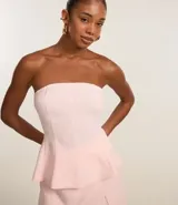 Blusa peplum de viscosa color rosa, con escote strapless, frunces en el busto y volado en la cintura.