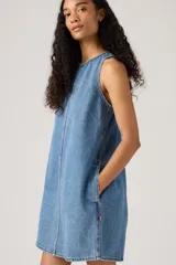 Vestido corto de denim azul, corte recto, sin mangas y con costuras verticales en el frente.