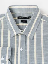 Camisa de manga larga con diseño de rayas verticales en tonos beige y blanco, cuello camisero y cierre frontal con botones.