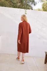 Abrigo oversize color ladrillo, confeccionado en lino pesado, con botonadura simple, bolsillos con solapa y ventilación trasera.