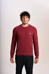 Sweater de punto grueso con cuello redondo y manga larga. Presenta un diseño de tejido acanalado y el logo de la marca bordado en el pecho.