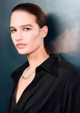 Camisa de tejido satinado color negro, de corte recto con diseño cruzado que se ajusta mediante un lazo lateral. Presenta cuello camisero, escote en V y mangas largas con puños anchos abotonados.