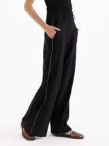 Pantalón sastre color negro de corte recto y tiro alto, confeccionado en mezcla de viscosa y elastano. Presenta bolsillos laterales, presillas para cinto y un delicado vivo decorativo a lo largo de los laterales.