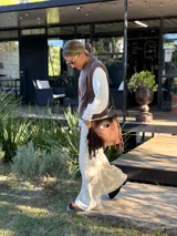 Chaleco tejido de punto en color chocolate, con cuello redondo y diseño sin mangas. Presenta un aplique frontal decorativo compuesto por tres figuras en forma de rombo en tonos tierra, bordeadas con hilo crudo.