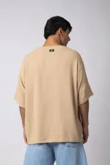 Remera de corte oversize confeccionada en tejido texturado tipo lino, de color beige, con cuello redondo amplio y mangas cortas de calce relajado.