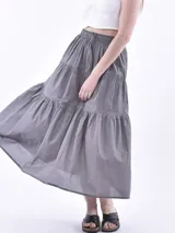 Falda larga gris oscuro de corte evase, con diseño en niveles y cintura elástica con cordón ajustable.