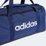 Bolso deportivo Adidas Linear mediano, de color azul marino con base negra y el nombre de la marca impreso en grande en color blanco en el frente. Cuenta con doble manija de mano y tira ajustable para el hombro.