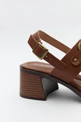 Sandalias de cuero color marrón con tacón cuadrado y hebilla lateral.