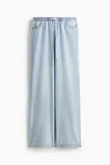Pantalón de denim celeste de corte holgado, con cintura elástica ajustable con cordón, bolsillos delanteros y traseros, y pierna ancha.