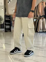 Pantalón cargo super baggy de jean color beige, de corte ancho con bolsillos laterales tipo cargo en las piernas y costuras reforzadas.
