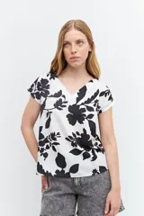 Blusa blanca con estampado de flores negras, escote en V y mangas cortas.