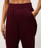 Pantalón jogger deportivo color bordó, con cintura elástica, bolsillos laterales y puños ajustados. Presenta recortes canelados en los laterales que aportan textura y diseño al modelo.