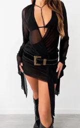 Vestido corto negro de gasa semitransparente, con escote en V cruzado, mangas largas acampanadas y un panel frontal drapeado que cae en forma de cola lateral.