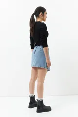 Minifalda de jean celeste con corte asimétrico, bolsillos de parche con solapa y tiras ajustables con hebillas en los laterales.