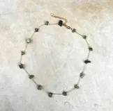 Collar delicado de cadena dorada con pequeñas piedras naturales en tonos variados, dispuestas de forma sutil a lo largo de la pieza.
