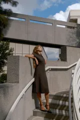 Vestido midi de punto en color marrón oscuro, con cuello redondo y escote en pico, manga corta y costuras marcadas en la parte frontal.