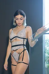 Conjunto de lencería de cuatro piezas compuesto por bralette, tanga, portaligas y ligas. Confeccionado en encaje premium bitono con detalles de tiras elásticas negras. El diseño incluye un bralette con escote profundo, tanga de tiro alto con tiras dobles regulables y portaligas con enganches desmontables.