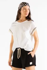 Remera de manga corta color blanco crema con detalle de flecos bordados en las mangas.