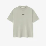 Camiseta de corte oversize confeccionada en algodón, con cuello redondo estructurado y pequeño logo metálico en el centro del pecho.