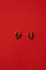 Aros tipo argolla con dije en forma de corazón esmaltado en color marrón chocolate y detalles metálicos dorados.