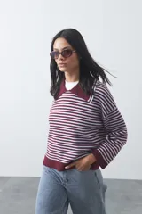 Sweater de punto a rayas horizontales en color bordó y celeste, con cuello polo y mangas largas con puños amplios. Presenta un diseño de calce relajado.