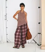 Pantalón estilo balloon de corte amplio y holgado, confeccionado en tejido de viscosa con estampado de cuadros en tonos bordó y blanco. Presenta cintura lisa y fruncido en los tobillos para un mayor volumen.