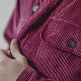 Camisa de pana azul con corte oversize, cuello clásico, cierre frontal de botones y dos bolsillos con solapa en el pecho.