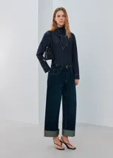 Camisa azul oscuro de denim con cuello alto y detalle de bufanda integrada en el mismo tejido.