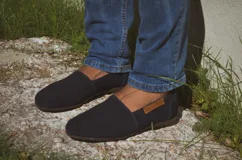 Alpargatas de gamuza color azul marino, con suela plana de goma y etiqueta lateral de cuerina con la marca grabada.