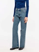 Jean de denim 100% algodón con lavado medio de aspecto vintage, tiro medio y corte flare con perneras ligeramente acampanadas.