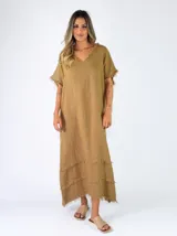 Vestido largo de lino color terracota, con escote en V y detalles de flecos en el cuello, mangas y en la parte inferior de la falda.