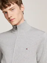 Cárdigan de punto color gris melange, confeccionado en mezcla de algodón y cachemira. Presenta cuello alto, cierre frontal de cremallera y el logo de Tommy Hilfiger bordado en el pecho.