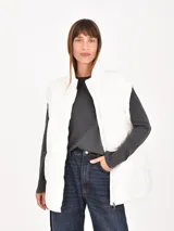 Chaleco puffer gris claro, con cuello alto y cierre frontal.