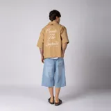 Camisa de manga corta azul oscuro de corte boxy, confeccionada en algodón. Presenta cuello camisero, cierre frontal con botones y un pequeño bordado en el pecho con las siglas 'VCP CNPT' y el número '333'.