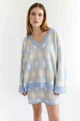 Sweater oversize con cuello en V y estampado de rombos en tonos lila, rosa y rojo. Tejido de lana artesanal.