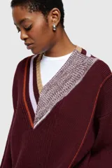 Sweater de punto color borgoña con cuello en V, diseño asimétrico con rayas en contraste y detalle de tejido texturizado en un lateral.