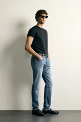 Jeans slim fit de color negro para hombre, con tiro medio, diseño de cinco bolsillos y cierre frontal con cremallera y botón.