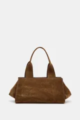 Bolso de mano de formato alargado, confeccionado en serraje (gamuza) color marrón. Presenta doble asa de hombro y cierre principal mediante cremallera. Incluye un bolsillo interior con cremallera.