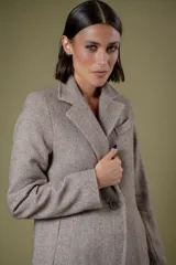 Tapado de corte sastre con diseño de espiga en tonos blanco y negro. Cuenta con solapas clásicas, cierre frontal de un botón y bolsillos laterales.