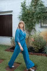 Enterito de mujer color azul piedra, con escote en V, mangas tipo capa y cintura fruncida elástica. El pantalón es de pierna ancha y fluida.