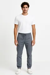 Pantalon tipo cargo de algodón en color gris, con cintura elástica ajustable mediante cordón, bolsillos laterales tipo cargo y puños elásticos en los tobillos.
