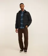 Campera puffer negra con cuello alto, cierre frontal con botones a presión, bolsillos laterales y un bolsillo cargo en el pecho. Presenta un diseño acolchado y forro interior suave.