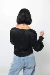 Camisa tipo blusa cruzada de seda negra, con escote en V profundo, mangas largas con puños abotonados y lazo lateral para anudar en la cintura.