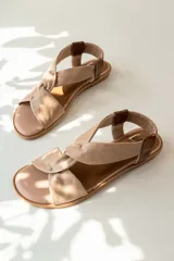 Sandalias chatitas de cuero en tono nude, con diseño de tiras cruzadas en el empeine y elástico en el talón para mayor ajuste. Presentan una plantilla acolchada y detalles en cuero charolado en la parte posterior.