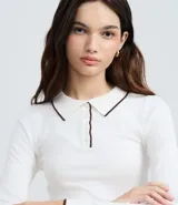 Blusa de punto color blanco con cuello polo, manga larga y detalles de ribete en contraste color negro en el cuello, puños y ruedo. Confeccionada en mezcla de viscosa, poliéster y poliamida.