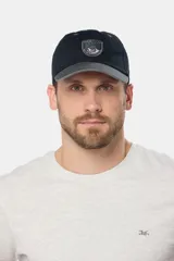 Gorro visera de lona azul marino, con visera curva en tono contrastante y parche tejido frontal con diseño gráfico.