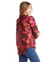 Blusa de gasa con estampado abstracto en tonos marrones, naranjas y fucsias. Presenta cuello mao con escote en V y mangas largas con sistema de ajuste mediante presilla y botón.