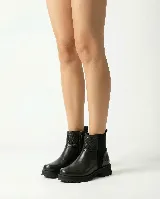 Bota corta de cuero color marrón, con diseño que combina cuero liso y sectores con textura grabada. Presenta una base robusta con taco medio y cierre lateral para facilitar el calce.