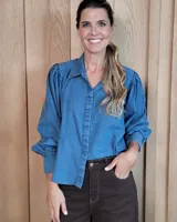 Camisa de jean azul con mangas largas abullonadas, puños ajustados y cuello clásico.